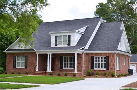 red brick house with grey metal roof|red brick house black shutters.